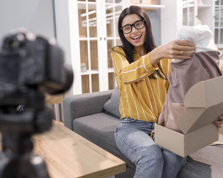 female vlogger home with camera unboxing clothes