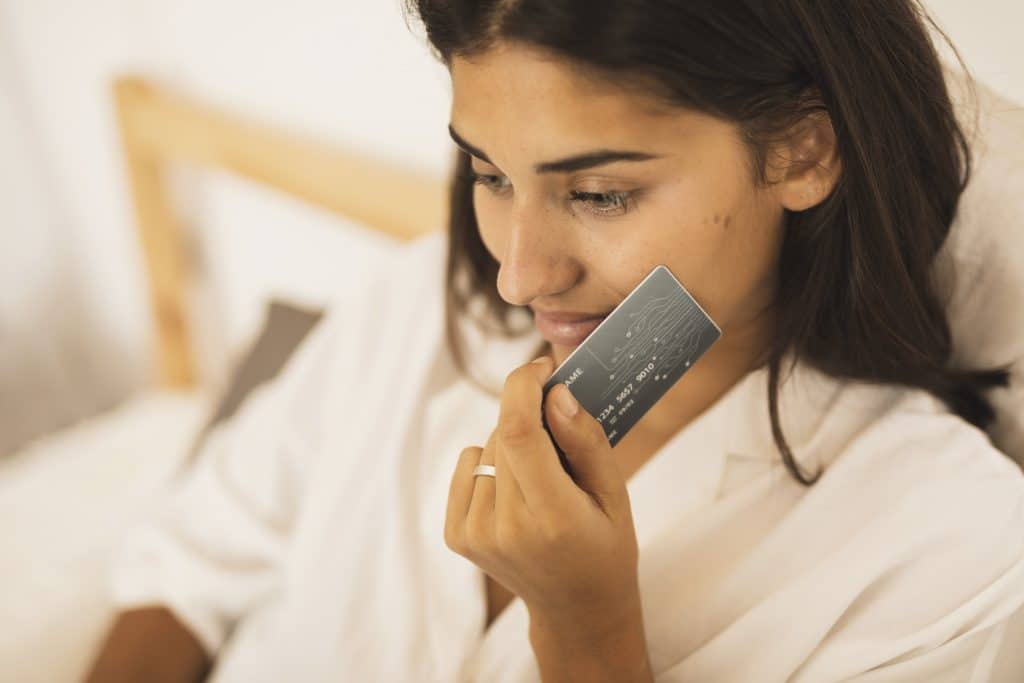 woman holding credit card her cheek